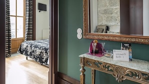 Une chambre d’hôtel avec un lit, un miroir, une console sur laquelle est posé un panneau, et une vue sur l’extérieur.