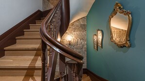 Un escalier en bois, un mur en pierre et un mur de couleur turquoise orné de miroirs décoratifs.