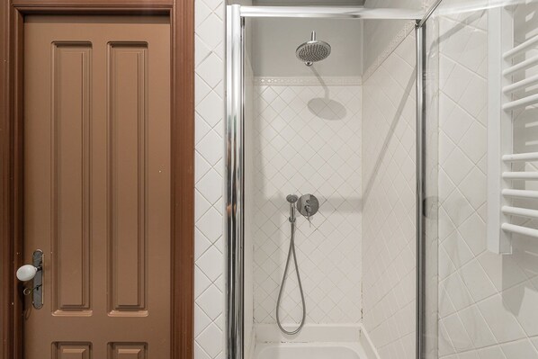 Un baño con ducha, una puerta y un perchero para toallas.
