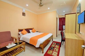 A hotel room with a bed, a chair, a desk, and a television. - Hotel Sam-bit International Puri - Walking Distance To Golden Sea Beach (Puri)