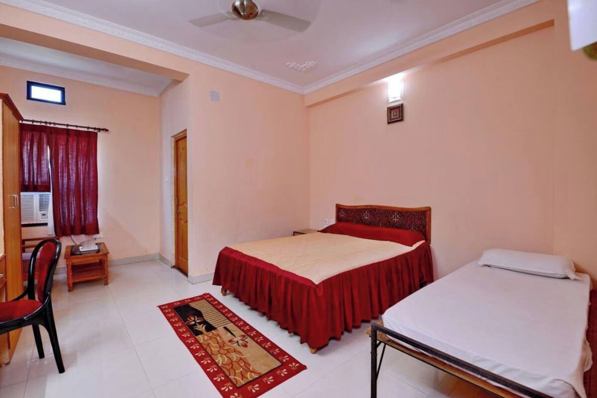 A bedroom with a bed, a smaller bed, a desk, a chair, and a ceiling fan.