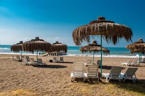 A beach with thatched umbrellas and white lounge chairs. - Doramar Resort Aqua Tatilkoyu (Erdemli)