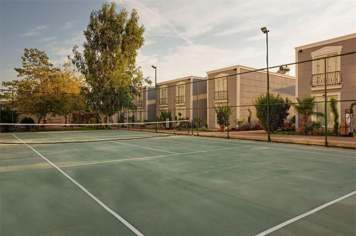 Cancha de tenis exterior con red, rodeada de edificios con balcones y ventanas.