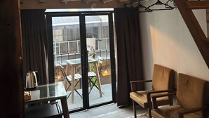 A loft-style room with a glass door leading to a patio, a small table with a kettle, and two chairs. - Mingle Highstreet (Kuala Lumpur)