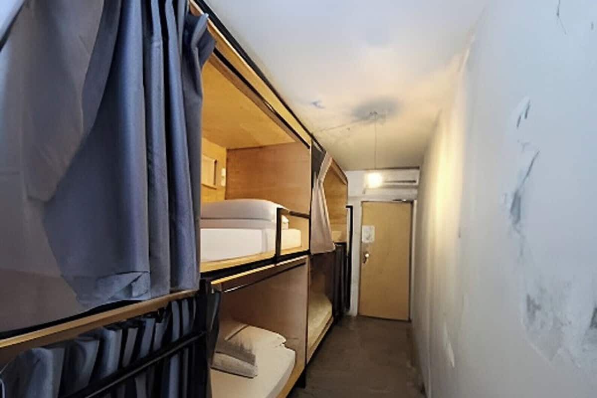 A narrow corridor with bunk beds on one side and a door at the end.