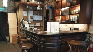 A bar area with a dark counter, wooden stools, and a brick wall. - Mingle Highstreet (Kuala Lumpur)