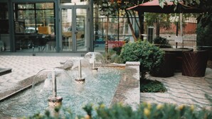 A water feature with multiple fountains, surrounded by potted plants and outdoor seating. - Monday Royal Apart Hotel (Tashkent)