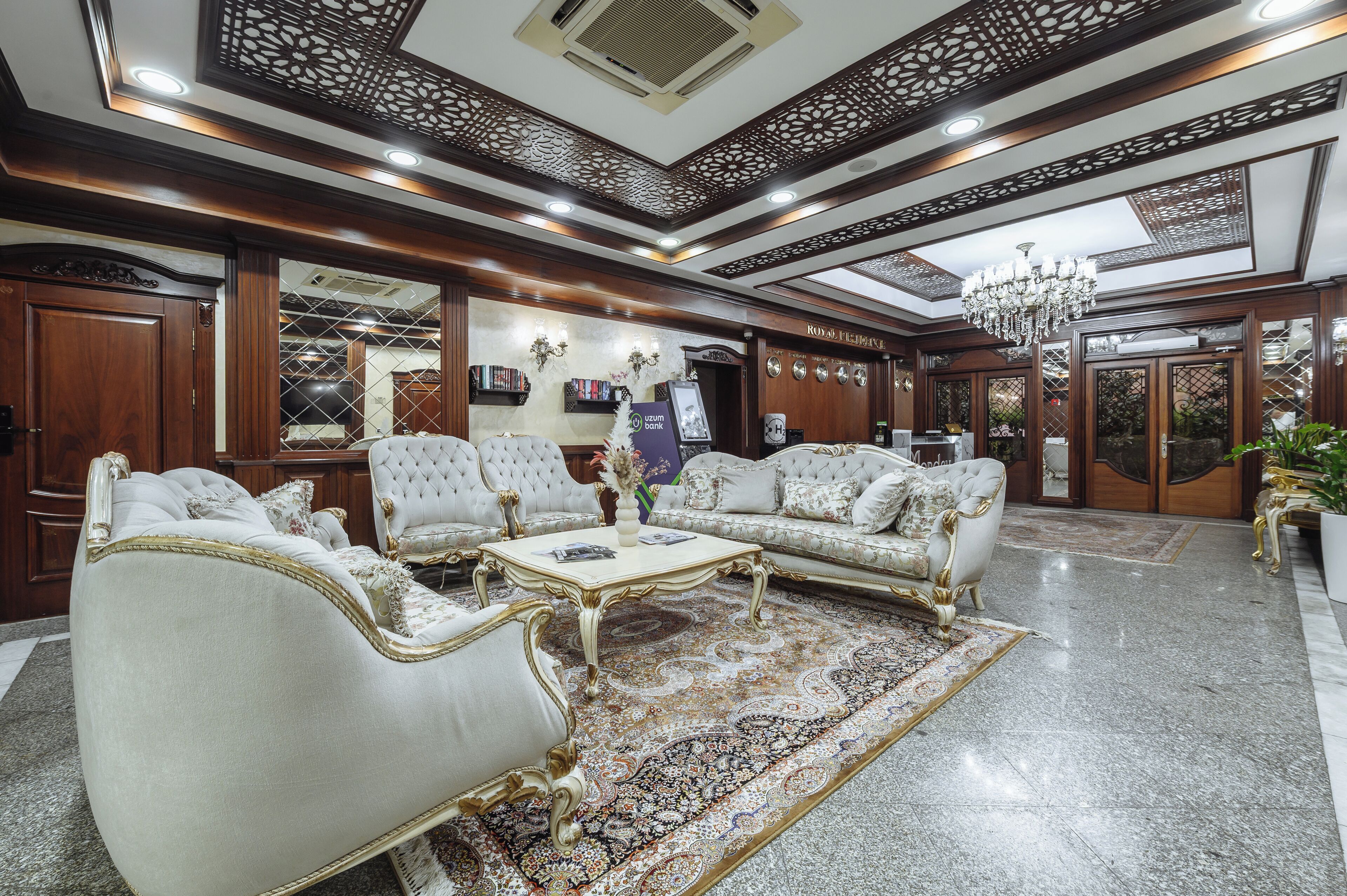 A luxurious lobby with ornate wood paneling, a chandelier, and plush seating.