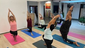 A yoga class in a modern room with wooden floors and large windows. - Namma Ashram (Bengaluru)