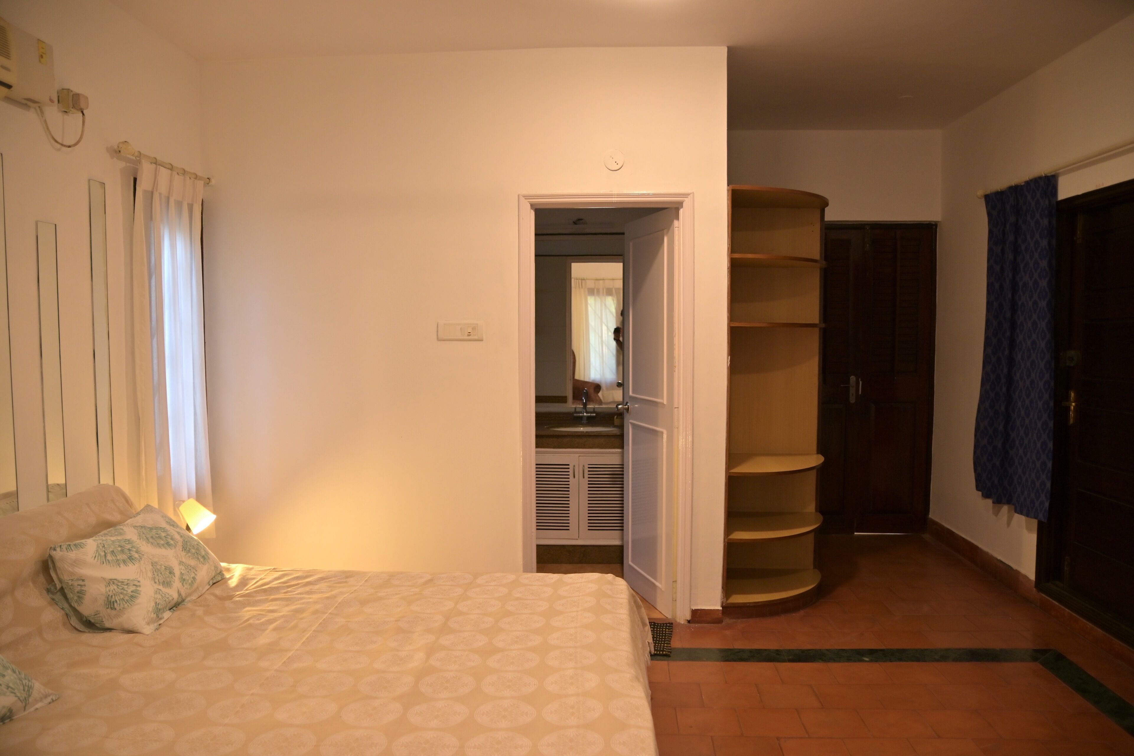 A bedroom with a bed, a wardrobe, and a bathroom visible through an open door.