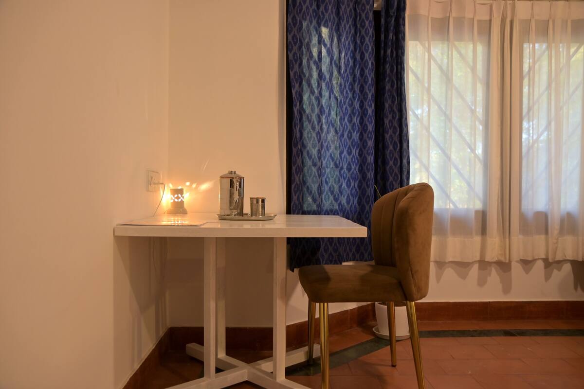 Uma pequena área de refeições com uma mesa branca, uma cadeira e um luminário decorativo.