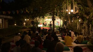 An outdoor event with a stage and audience seated on the ground. - Namma Ashram (Bengaluru)