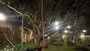 A tree with a swing hanging from it, surrounded by a well-maintained lawn and garden. - Namma Ashram (Bengaluru)