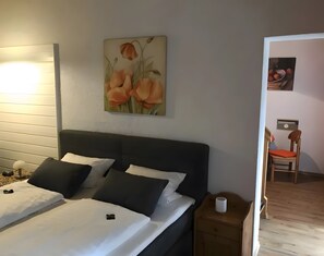 A bedroom with a bed, bedside tables, a nightstand, a painting, and a chair in the corner. - Apartment in A Hotel '1' with Mountain View, Private Terrace and Wi-Fi (Lindberg)