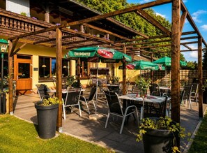 An outdoor seating area with tables and chairs, green umbrellas, and a wooden pergola structure. - Hotel Schachten – Apartment 1 mit Bergblick, Frühstück inklusive & Shuttle-Service (Lindberg)