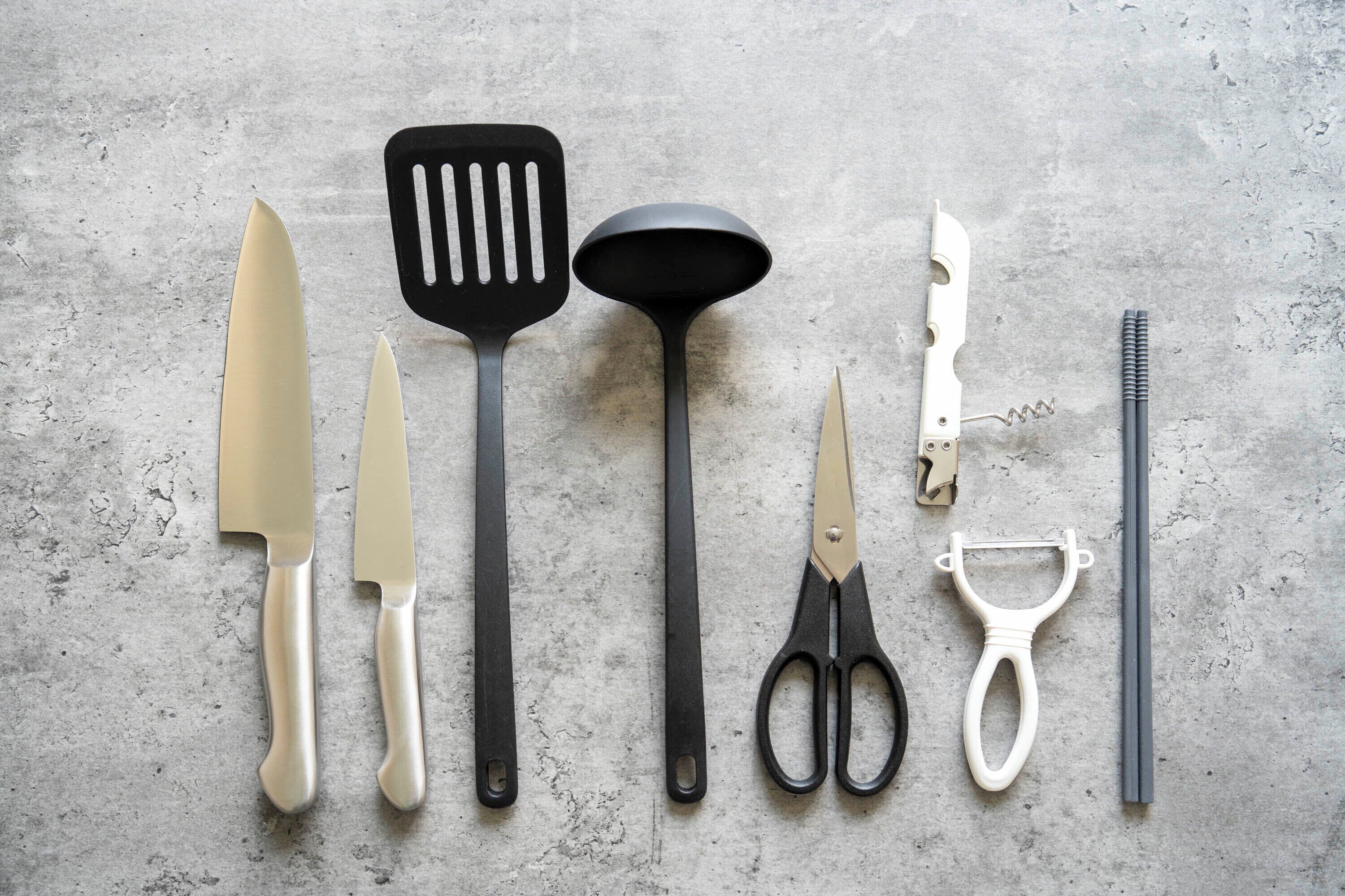 Various kitchen utensils laid out on a textured surface.