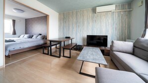Un salon moderne avec un canapé, une table basse, un téléviseur et un lit.