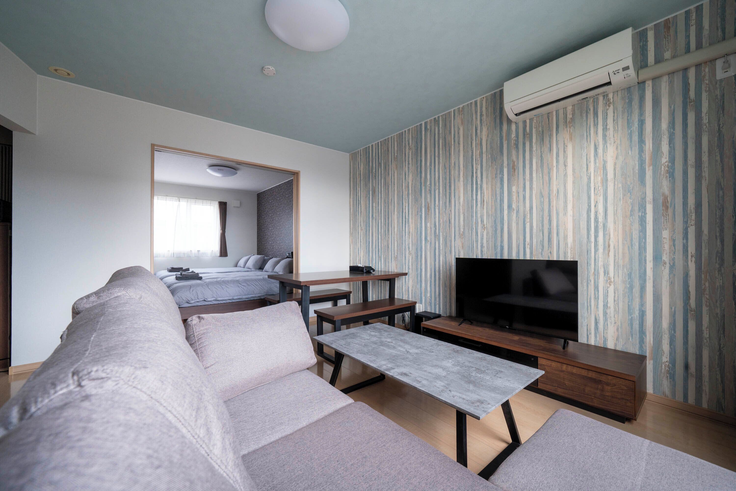 Una sala de estar moderna con un sofá, una mesa de centro, un televisor y un comedor.