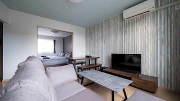 Una sala de estar moderna con un sofá, una mesa de centro, un televisor y un comedor.