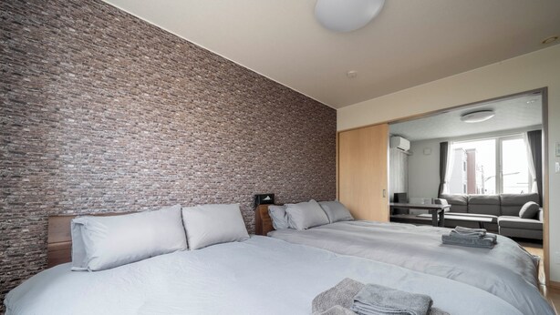 Une chambre d’hôtel moderne avec deux grands lits, un mur décoratif en briques, une tête de lit en bois et un grand miroir qui reflète la pièce.