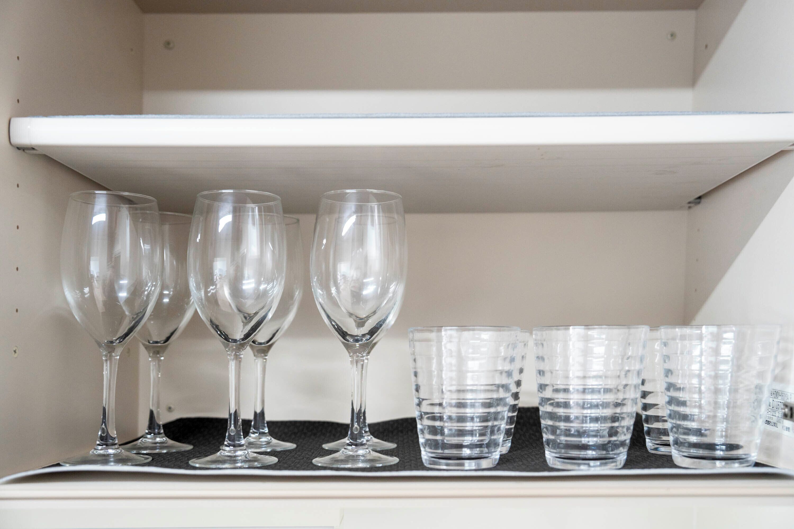 Una estantería con copas de vino y vasos de agua.