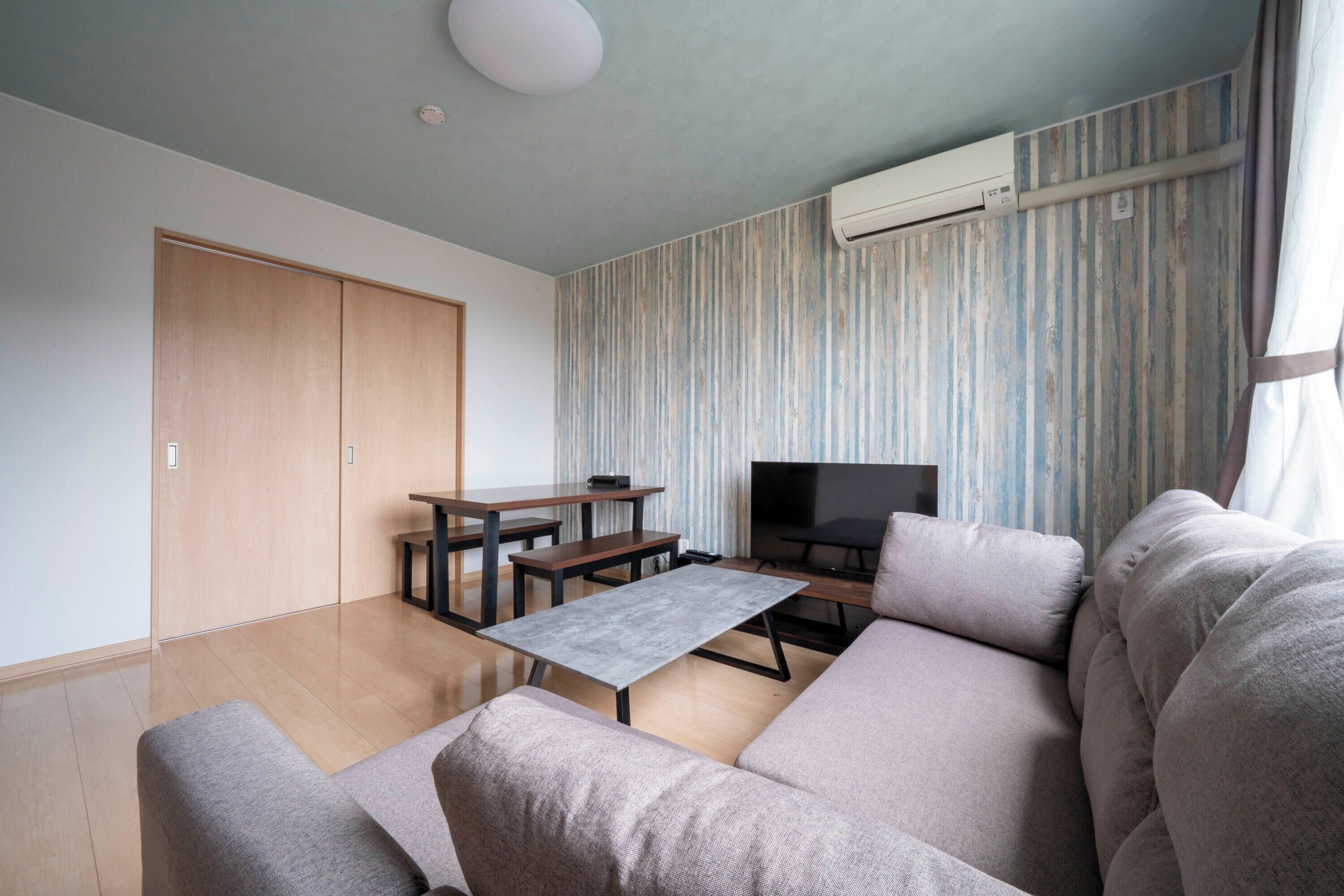 A modern living room with a sofa, a coffee table, a TV, and a wooden wardrobe.