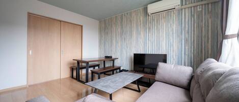 A modern living room with a sofa, a coffee table, a TV, and a wooden wardrobe.
