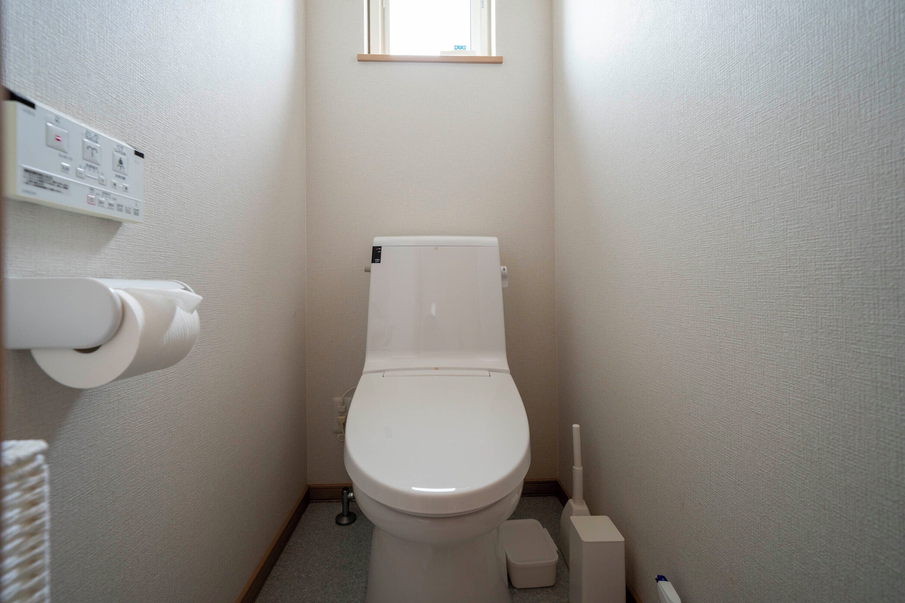 Une petite salle de bain propre, équipée de toilettes, d’un porte-rouleau de papier toilette et d’un bidet.
