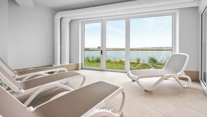 A modern room with large windows, a pool view, and three lounge chairs.