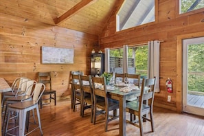 Un coin repas en bois avec une table dressée pour six personnes, entourée de chaises.