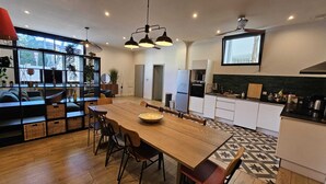 Una cocina moderna con una amplia mesa de madera, electrodomésticos integrados y vistas al exterior a través de grandes ventanales.