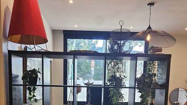 Una sala de estar moderna con una estantería negra, muebles de madera y una lámpara roja.