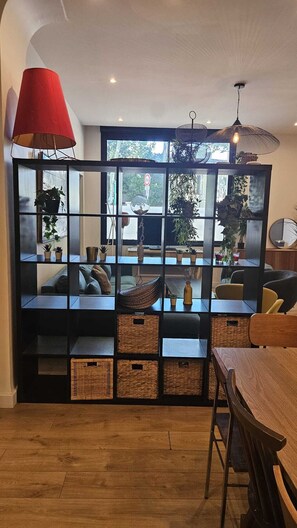 A modern living room with a black shelving unit, wooden furniture, and a red lamp.