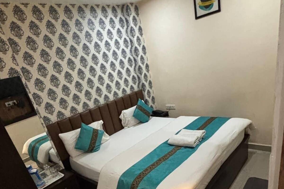 A neatly made bed with a patterned headboard, a ceiling fan, and a framed picture on the wall.