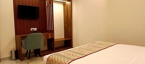 A hotel room with a bed, a desk, a chair, a TV mounted on the wall, and a trash bin. - Chocolate Inn Patna (Patna)