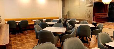 Un restaurante con suelo de madera, sillas tapizadas en verde y un banco de madera a lo largo de la pared.