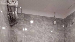 Un baño moderno con pared de mármol, ducha, inodoro y perchero para toallas.