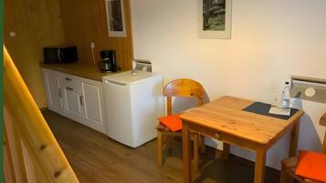 A compact kitchen with a washing machine, a coffee maker, and a table with chairs.
