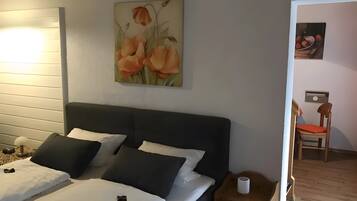 Une chambre à coucher avec un lit, des tables de chevet, une commode, un tableau et une chaise dans un coin.