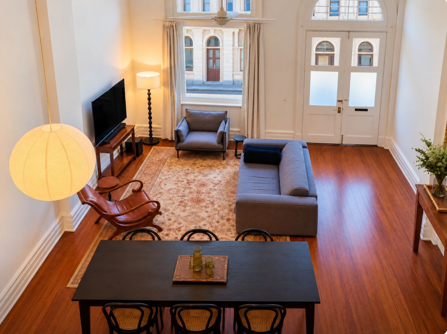 A living room with a sofa, armchair, TV, and a dining table with chairs.