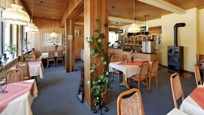 A restaurant with wooden interiors, tables with white and red tablecloths, and a kitchen in the background. - Apartment in A Hotel '5' with Mountain View, Private Terrace and Wi-Fi (Lindberg)