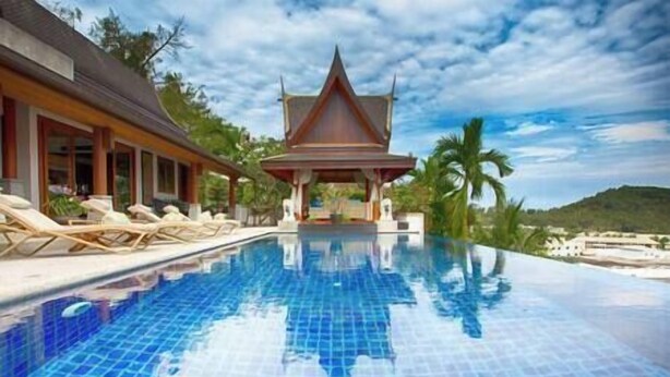 A swimming pool with a tiled surface, a covered pavilion, and lounge chairs along the poolside.