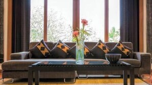 A living room with a sofa, a coffee table, and a vase with flowers.