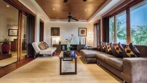 A spacious living room with a large sofa, a coffee table, and a ceiling fan.