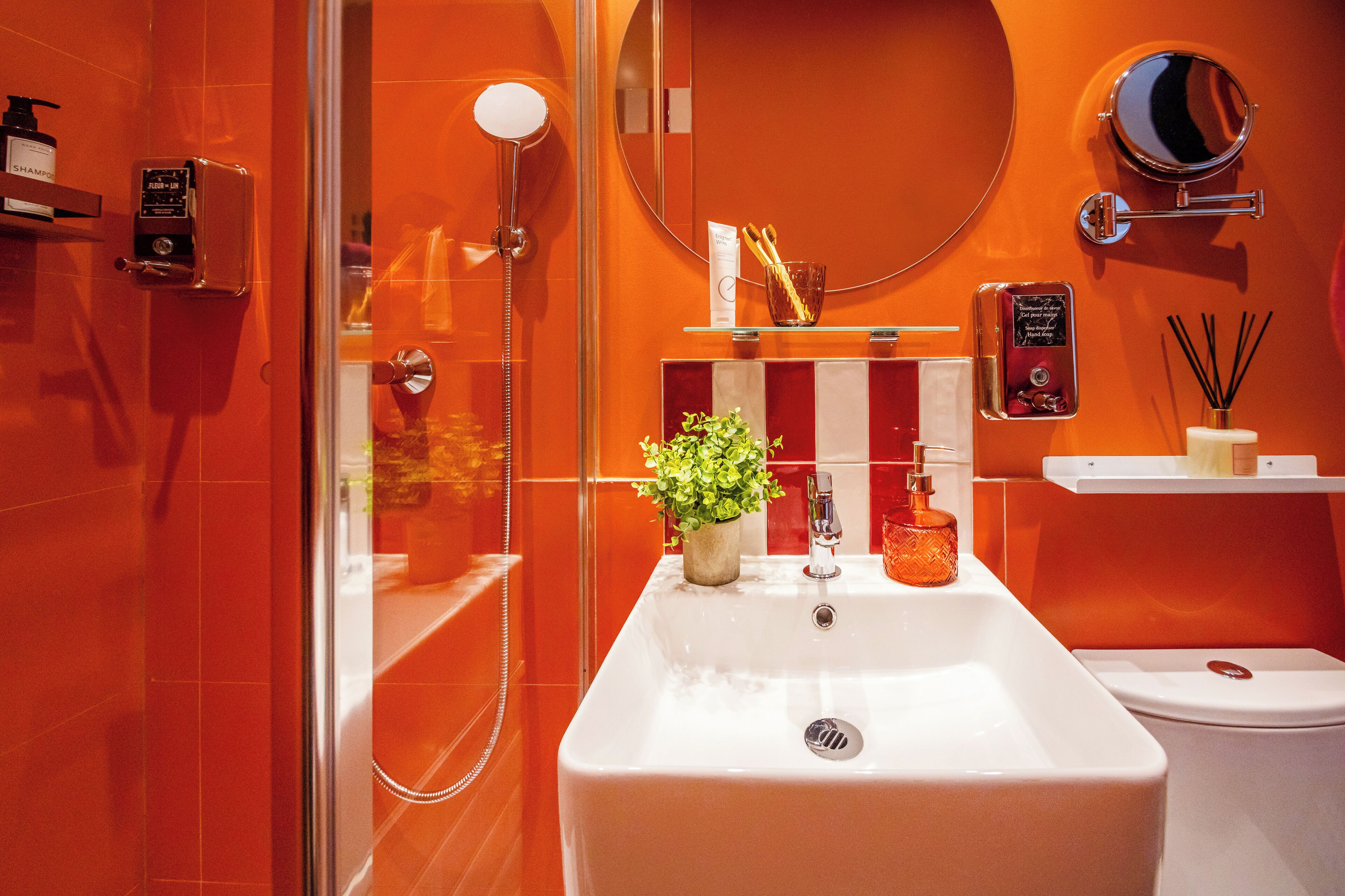 A modern bathroom with a large sink, a handheld shower, and a toilet.