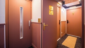 Un couloir d’hôtel avec des portes marron, un panneau indiquant le 6e étage et un paillasson à motifs.