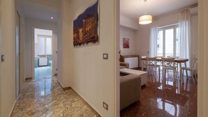 A hallway with a marble floor, a dining area with a table and chairs, and a painting on the wall. - GuestHost - Trastevere Apartment Roma Portuense (Rome)