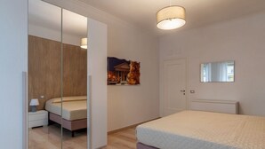 A bedroom with a bed, a nightstand, a mirror, and a door. - GuestHost - Trastevere Apartment Roma Portuense (Rome)