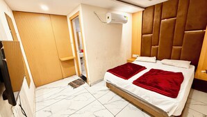 Un dormitorio con cama, armario de madera, unidad de aire acondicionado y puerta de baño.