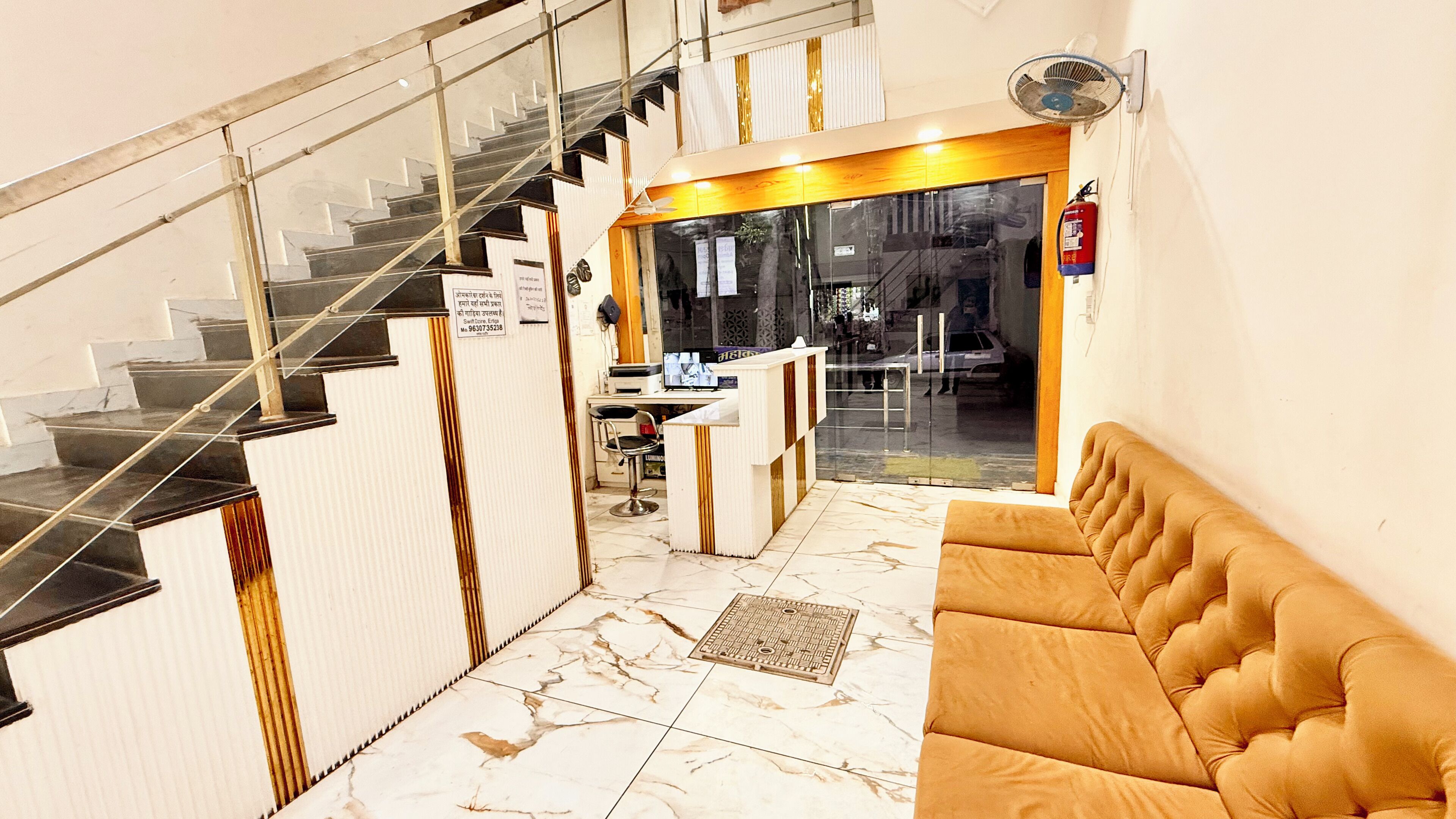 Un hall de hotel con suelo de mármol, una recepción, un sofá y una escalera.